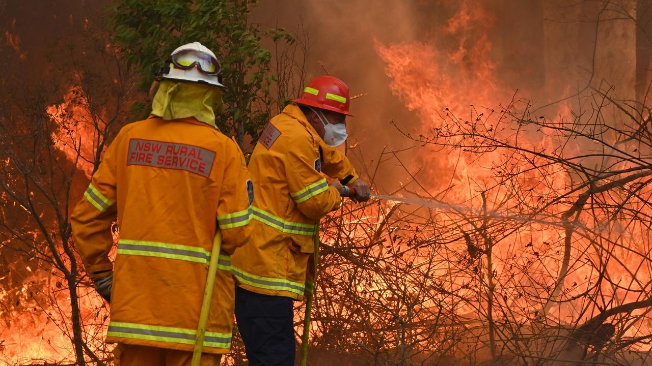 Firefighters tackle a bushfire to save a home in Taree, 350km north of Sydney. Picture: Peter Parks/AFP