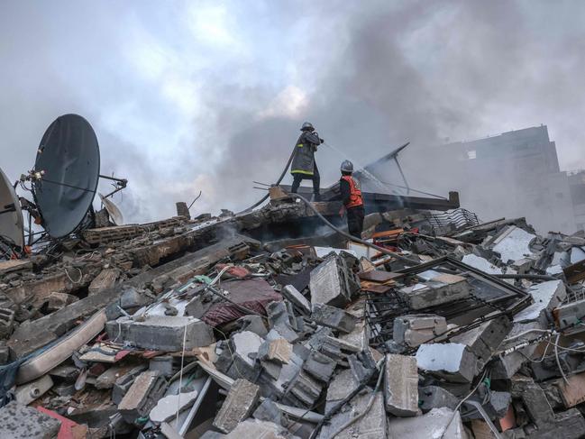 Firefighters work to extinguish a fire that was raging in a residential building destroyed by Israeli air strikes in Gaza City. Picture: AFP