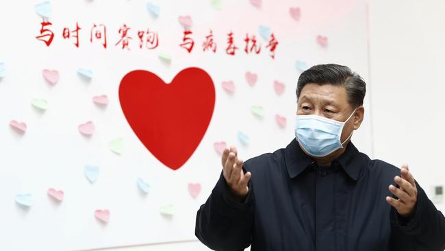 Chinese President Xi Jinping stands near a sign reading "Race against time, Fight the Virus" during an inspection of the centre for disease control and prevention of Chaoyang District in Beijing. Xi is promising tax cuts and other aid to industries hurt by a virus outbreak in a renewed effort to rein in the rising damage to the economy.