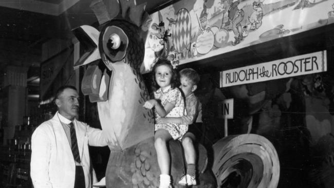 John Martin & Co. Ltd., Rundle Street, Adelaide. Children sitting on Rudolph the Rooster in Easter Cave, 1937.