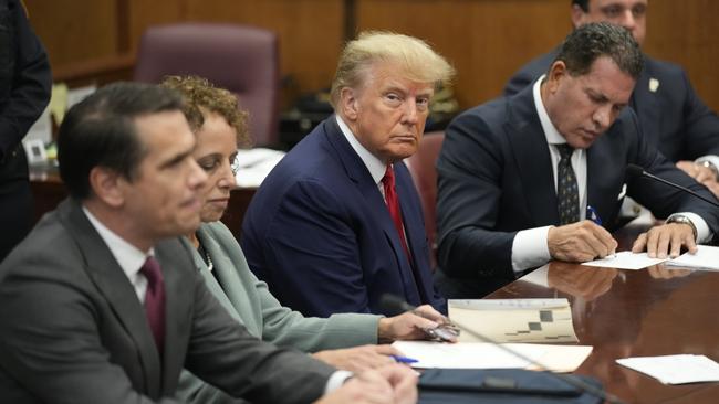 Donald Trump looks grimly at the camera as he sits with his legal defence team during his arraignment in a Manhattan court. Picture: Bloomberg via Getty Images