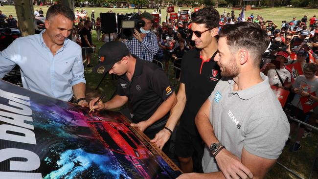 Peter Malinauskas holds a poster as driver Todd Hazelwood signs it as Nick Percat and Scott Pye look on. Picture: Emma Brasier