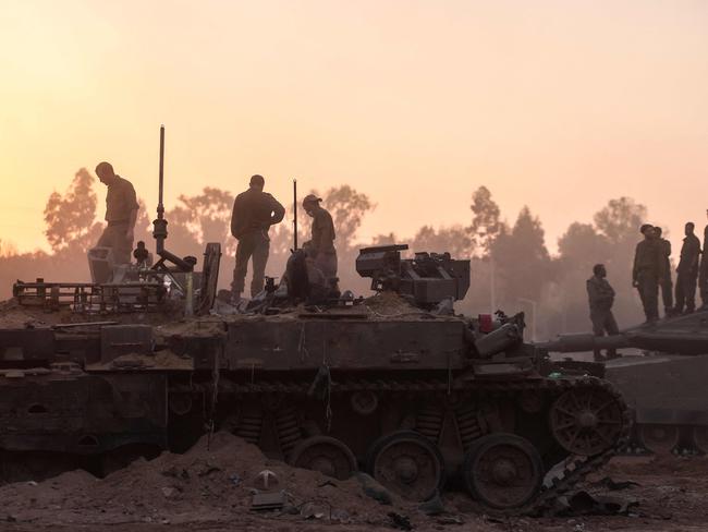 A picture taken in southern Israel near the border with the Gaza Strip on December 11, 2023, shows Israeli army soldier working on tanks amid continuing battles between Israel and the militant group Hamas. (Photo by Menahem KAHANA / AFP)