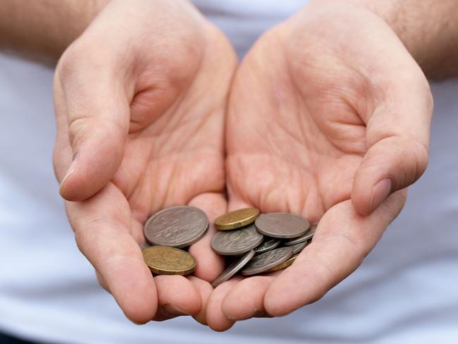 A caucasian man holds out some Australian coins; poor money generic hands