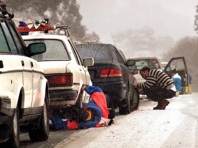 Motorists fix snow chains to their cars after heavy snow dump left the Thredbo road clogged with traffic.  New South Wales (NSW / Mountain / Weather