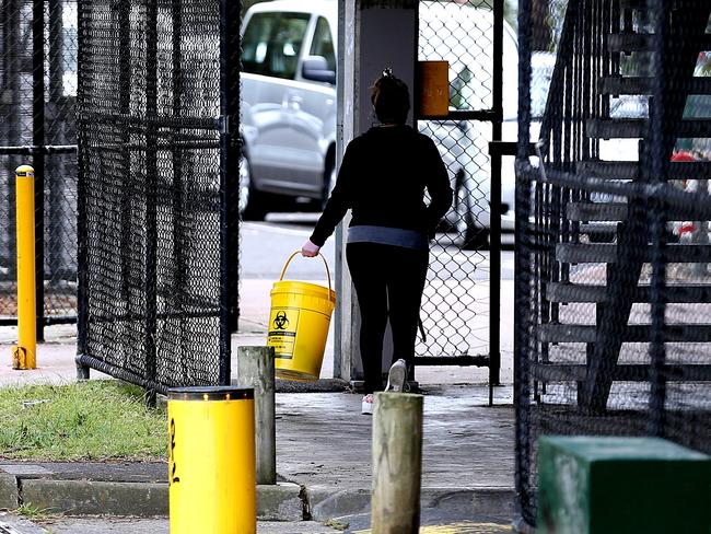 A person collects syringes from the ground in a carpark in Richmond.