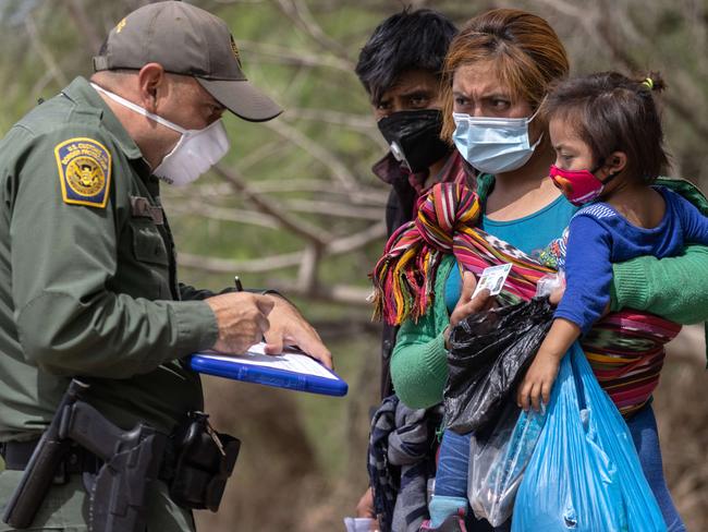 A border agent questions asylum seekers after they crossed the Rio Grande into Texas. Picture: AFP