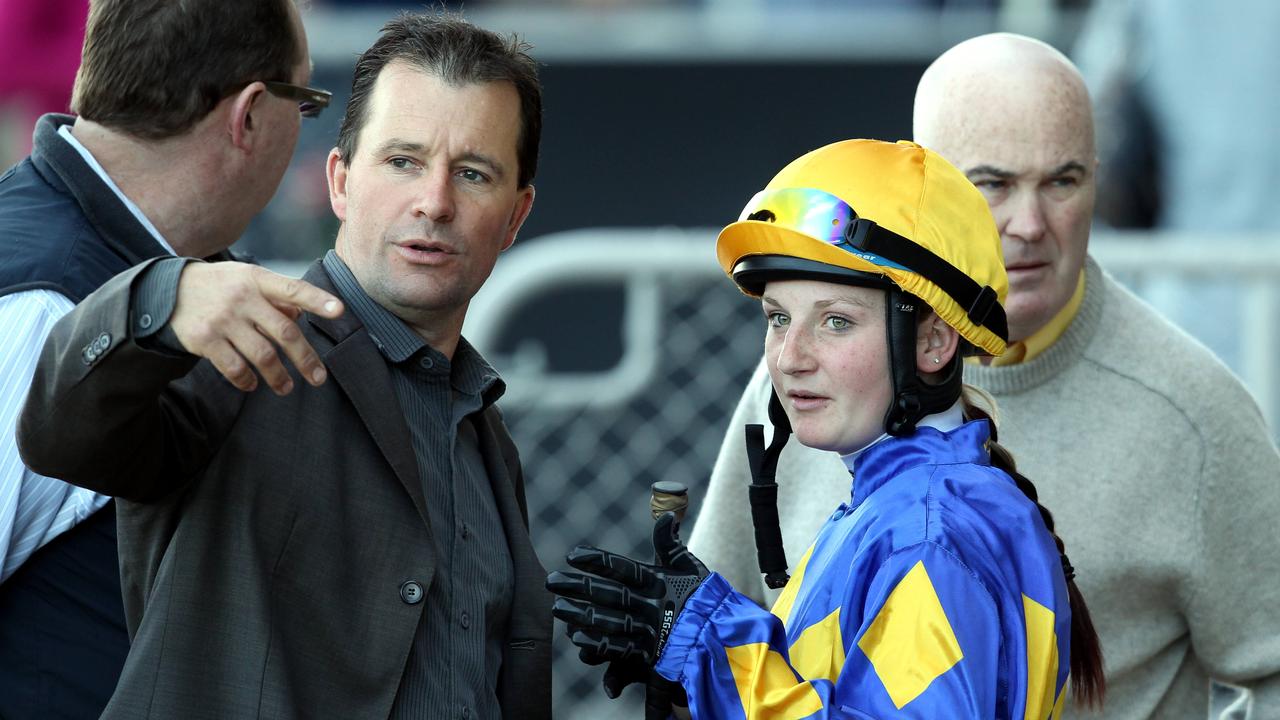 Apprentice jockey Jamie Kah talking to racehorse trainer John MacMillan.