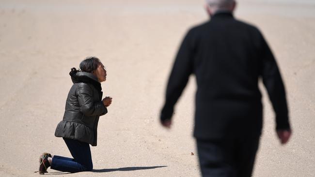 A woman prays on St Kilda Beach in Melbourne on Monday. Picture: AFP