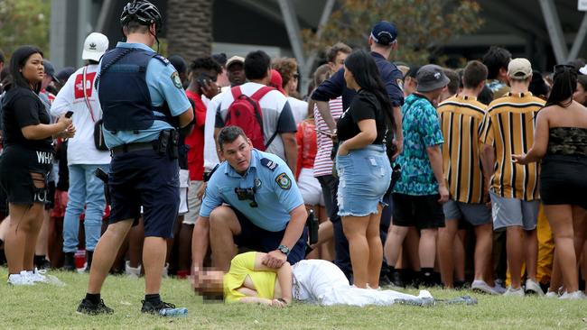 A girl is held in the recovery position by a police officer outside the Rolling Loud Festival on Sunday. Picture: Damian Shaw