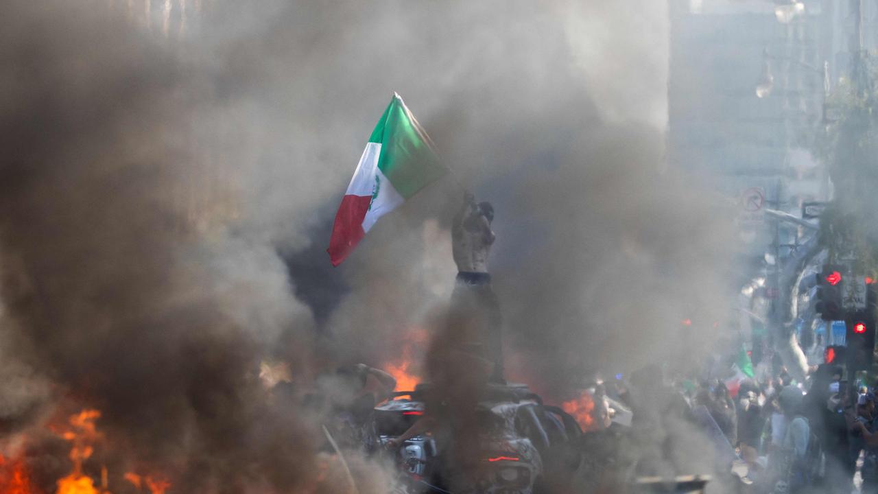 A man waves a Mexican flag while he stands on top of a car during the protests. Picture: Getty Images via AFP