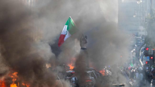 A man waves a Mexican flag while he stands on top of a car during the protests. Picture: Getty Images via AFP