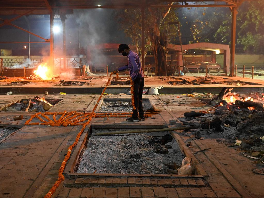 A crematorium staff places garlands before a cremation of a coronavirus victim at Nigambodh Ghat Crematorium, on the banks of the Yamuna river in New Delhi. Picture: AFP