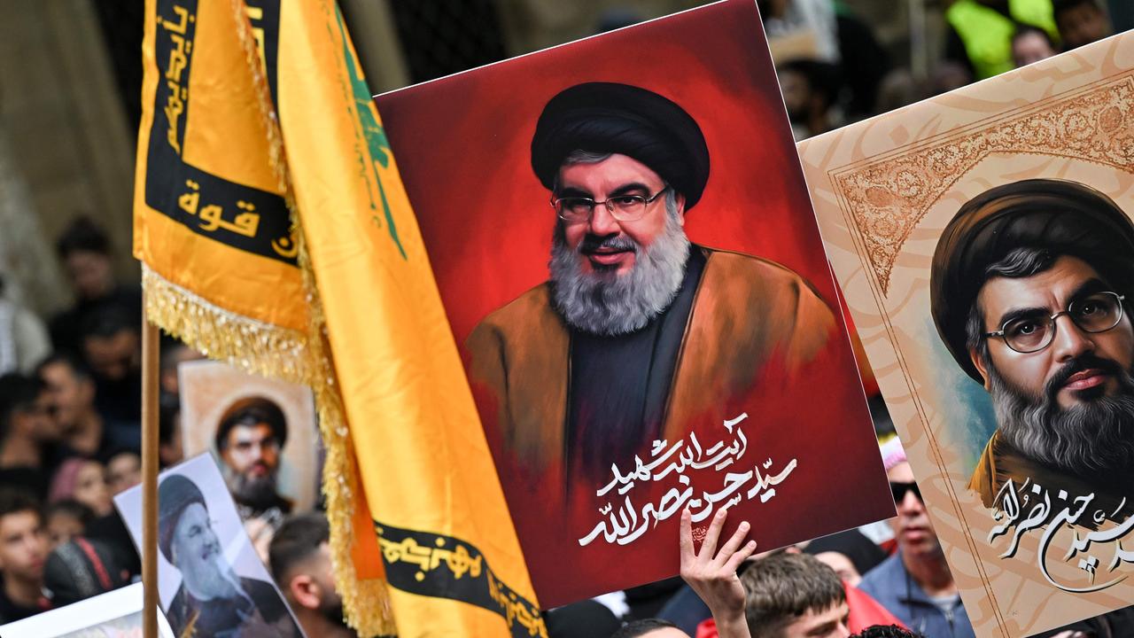 Demonstrators hold flags and pictures of Hassan Nasrallah, late leader of the Lebanese group Hezbollah, at a protest rally in the central business district of Sydney on September 29, 2024. (Photo by Saeed KHAN / AFP)