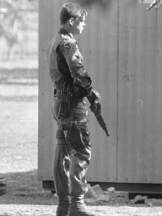 Police guard members of the Hells Angels while searching the BLONKS head quarters in 1992.