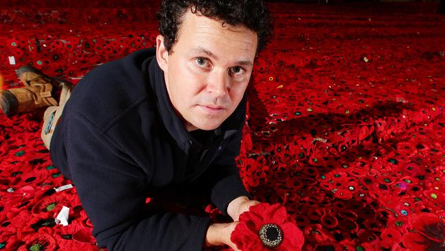 200,000 crochet poppies being installed in Fed Square for Anzac Day. Landscape Designer Phillip Johnson with some of the 200,000 crocheted poppies at Federation Square Picture: Norm Oorloff