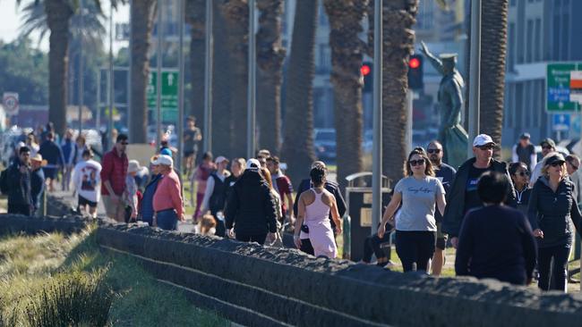 People walk along a walkway at Port Melbourne Beach in Melbourne. Picture: AAP.