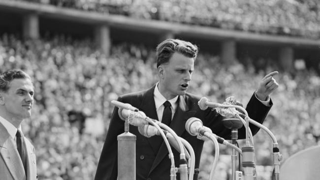 FILE - In this June 27, 1954 file photo, Evangelist Billy Graham speaks to over 100,000 Berliners at the Olympic Stadium in Berlin, Germany.   Graham, who transformed American religious life through his preaching and activism, becoming a counselor to presidents and the most widely heard Christian evangelist in history, has died. Spokesman Mark DeMoss says Graham, who long suffered from cancer, pneumonia and other ailments, died at his home in North Carolina on Wednesday, Feb. 21, 2018. He was 99. (AP Photo, File)