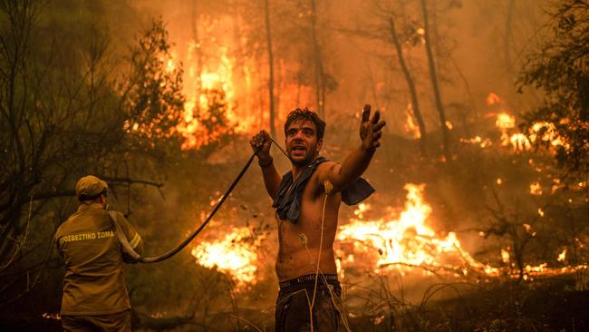 A resident gestures as he holds an empty water hose during an attempt to extinguish forest fires approaching the village of Pefki on Evia island, Greece’s second largest island. Picture: AFP