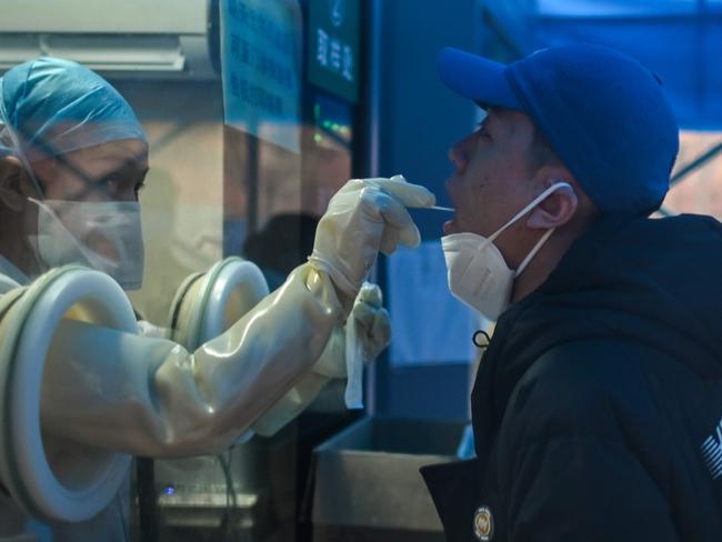 Even doctors were falling ill, but still working … a health worker takes a swab sample in Wuhan on February 7, 2021.