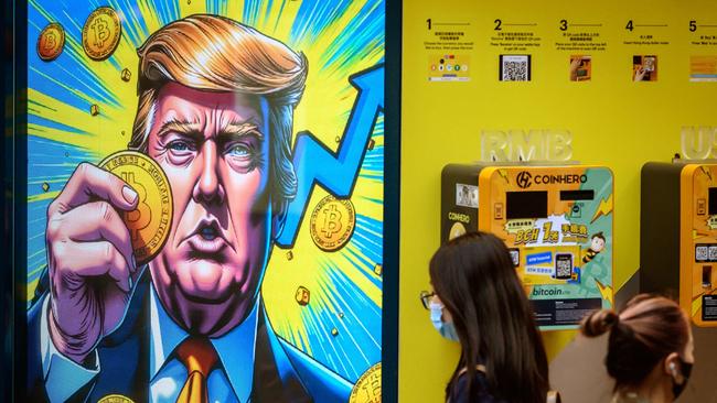 People walk past a cryptocurrency exchange office with a screen featuring US President Donald Trump holding cryptocurrency coins in Hong Kong. Picture: AFP