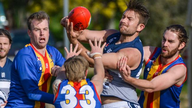 Henley’s Jack Enright handballs under pressure as Old Ignatians players swarm him. Picture: Brenton Edwards