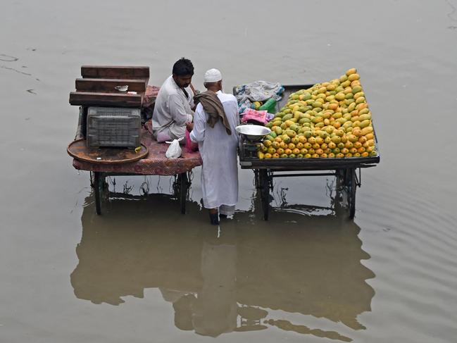 Fruit vendors stand in a flooded street in Karachi, Pakistan, on July 24, 2023. Picture: Rizwan Tabassum / AFP