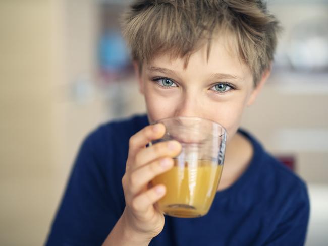 Portrait of a cute little boy aged 9 drinking a glass of orange juice Nikon D850