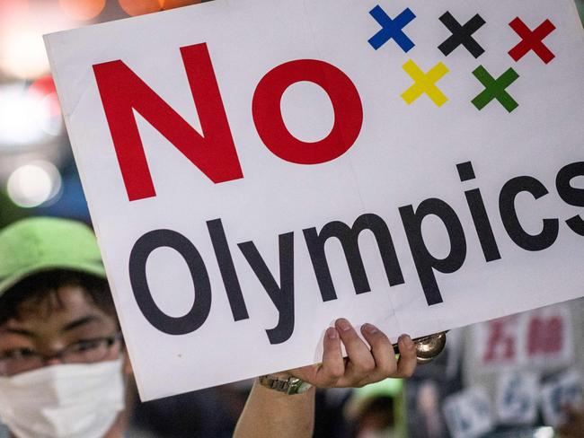 An anti-Olympic activist holds up a placard with a slogan reading 