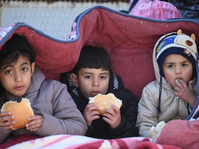 Children eat bread as they sit under a cover in the southeastern Turkish city of Kahramanmaras. Picture: AFP