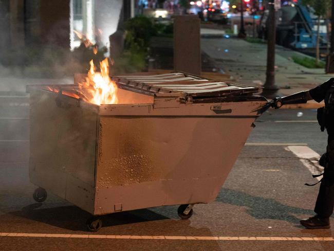 A police officer drags a dumpster on fire one block from the White House. Picture: AFP