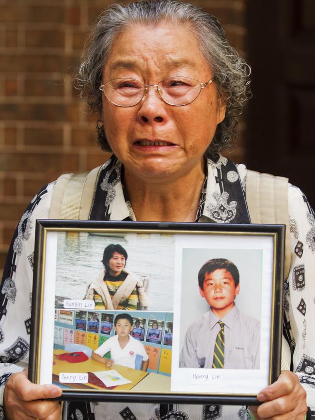 Yang Fei Lin holding up pictures of her daughter and grandsons killed by Robert Xie. Picture: Jenny Evans