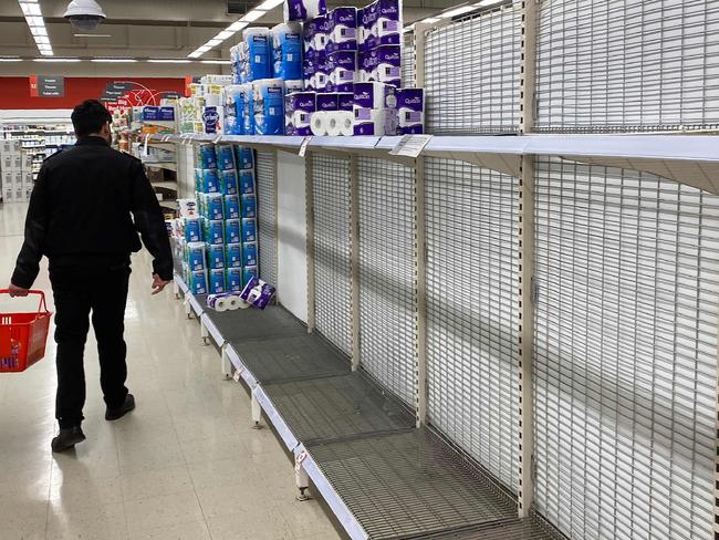 A shopper walks past near-empty shelves of toilet paper at a supermarket in a Melbourne on June 26, 2020. - Supermarkets imposed purchase limits on toilet paper across Australia on June 26 following panic buying by people rattled over a surge in coronavirus cases in the country's second-biggest city. (Photo by William WEST / AFP)