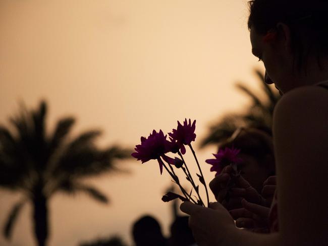 Kathleen Kerr, of Orlando, Fla., holds flowers before placing them down at a makeshift memorial for the victims of the mass shooting at the Pulse Orlando nightclub Tuesday, June 14, 2016, in Orlando. (AP Photo/David Goldman)