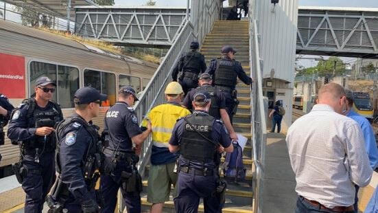 Police lead a protester away after he blocked tracks at Brisbane's Bowen Hills train station. Picture: Matt Watson.