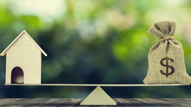 Money and home,loan,mortgage. Change home into cash concept. US Dollar in sack bag, Wooden house model put on scales on wood table with green tree bokeh as background. Balance home and debt.