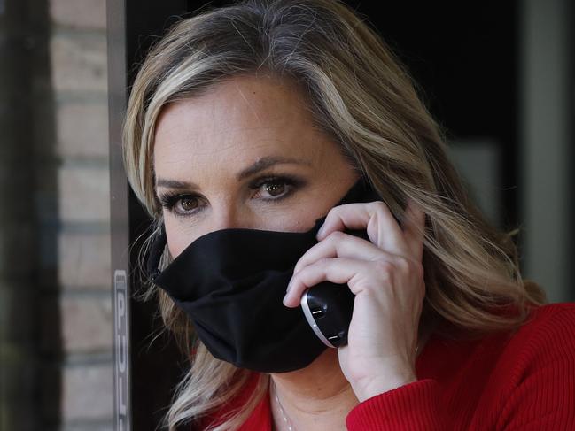 Amid concerns of the spread of COVID-19, salon owner Shelley Luther wears a mask as she talks on phone just outside her reopened Salon A la Mode in Dallas, Friday, April 24, 2020. Hair salons have not been cleared for reopening in Texas. (AP Photo/LM Otero)