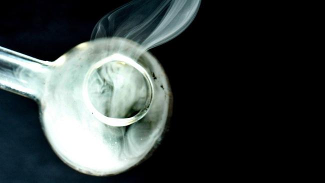 Methamphetamine pure crystals being heated in a glass pipe by a police drugs officer during a controlled demonstration.