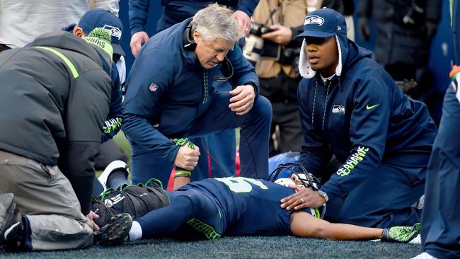 Head coach Pete Carroll of the Seattle Seahawks tends to wide receiver Tyler Lockett #16 after he was injured in a play.