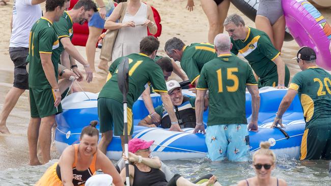 Former Wallaby and spinal injury victim Richard Tombs (middle) is helped into an inflatable boat at the start of the second wave during the annual Manly Inflatable Boat Race at Shelly Beach at Manly on Sunday, 23 February, 2020. (AAP IMAGE / Troy Snook)