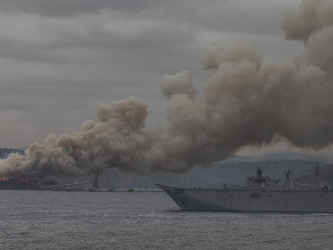 Eden-HMAS Adelaide arrived in Eden on Monday morning. The local chipmill is still ablaze  and is burning in the background.Picture Gary Ramage