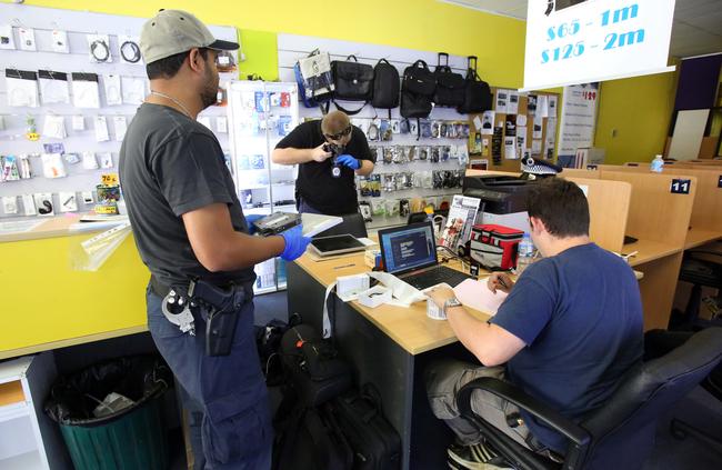 Police at a Kings Cross pawn shop in 2015. Police allege a syndicate stole more than 800 computers from schools.