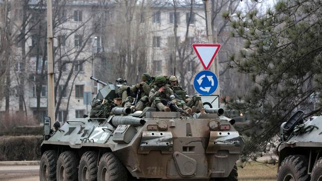 Servicemen ride atop a Russian armored vehicle in Armyansk, Crimea, on February 25, 2022. - Ukrainian forces fought off Russian invaders in the streets of the capital Kyiv on February 25, 2022, as President Volodymyr Zelensky accused Moscow of targeting civilians and called for more international sanctions. Pre-dawn blasts in Kyiv set off a second day of violence after Russian President Vladimir Putin defied Western warnings to unleash a full-scale invasion on on February 24, 2022, that quickly claimed dozens of lives and displaced at least 100,000 people. (Photo by STRINGER / AFP)
