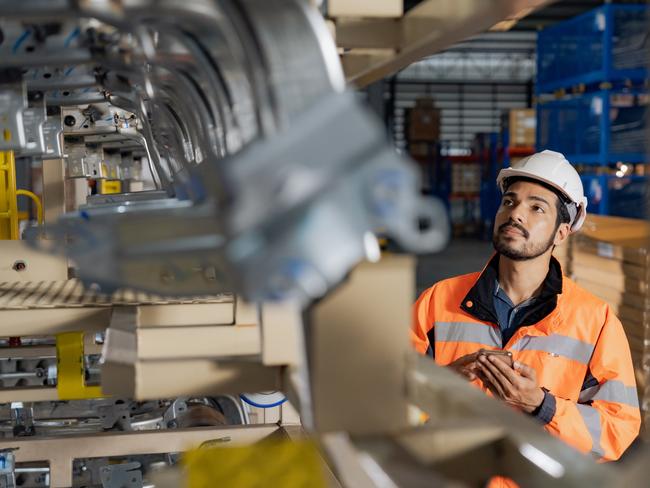 Young man industrial engineer wearing a white helmet while check the welding on the production line in the factory.