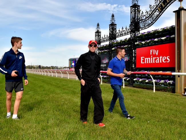 Jockeys Sam Clipperton, Tommy Berry and Mitch Bell walk the track at Flemington.