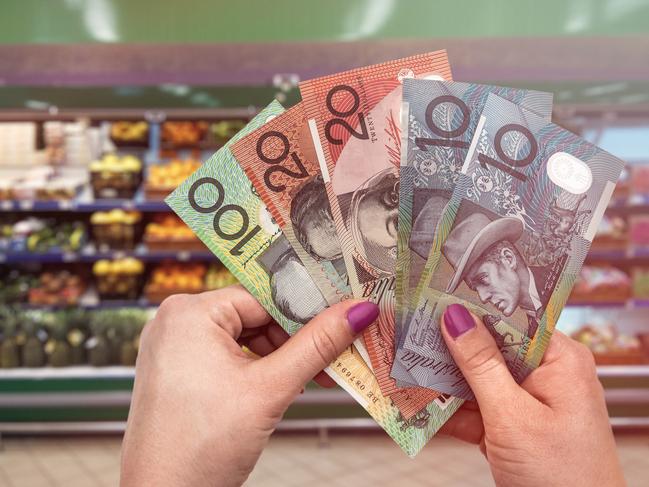 Buying fresh fruits and vegetables, hand with dollars, Australian money at supermarket