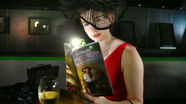 Annabel Pike browses the form guide using a torch after a power outage at Eagle Farm on Tuesday. Picture: Liam Kidston.