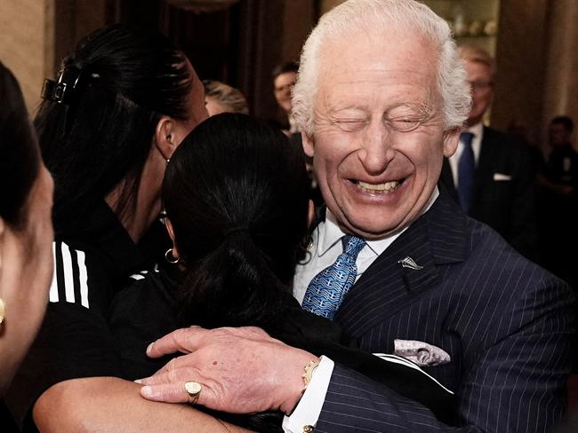 Britain's King Charles III reacts as he is hugged by members of New Zealand's Black Ferns rugby union team, at Buckingham Palace in central London on September 11, 2024. (Photo by Aaron Chown / POOL / AFP)