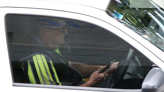 The Queensland Road Rules say a driver “must not use a mobile phone that the driver is holding … while the vehicle is moving, or is stationary but not parked”. Picture AAP/ David Clark