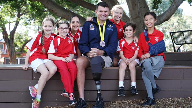 Invictus Games athlete Garry Robinson with Canterbury South Public School students (from left) Elizabeth Turner, 8, Georgia Scrivener, 9, Melia Antonopolous, 10, Alice Bursill Dickinson, 9, Elliot Foxlee, 8, and Beatrice Shimada, 9. Picture: David Swift